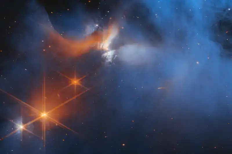 Chamaeleon I bulutunun merkez bölgesinde, arka plandaki yıldızlardan (turuncu) gelen ışık, soğuk, ince toz ve gaz bulutundaki (mavi) elementleri ortaya çıkarır NASA, ESA, CSA ve M. McClure (Leiden)